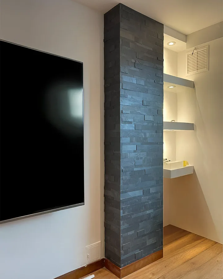 Columna decorativa revestida con piedra flexible negra 3D en sala moderna.