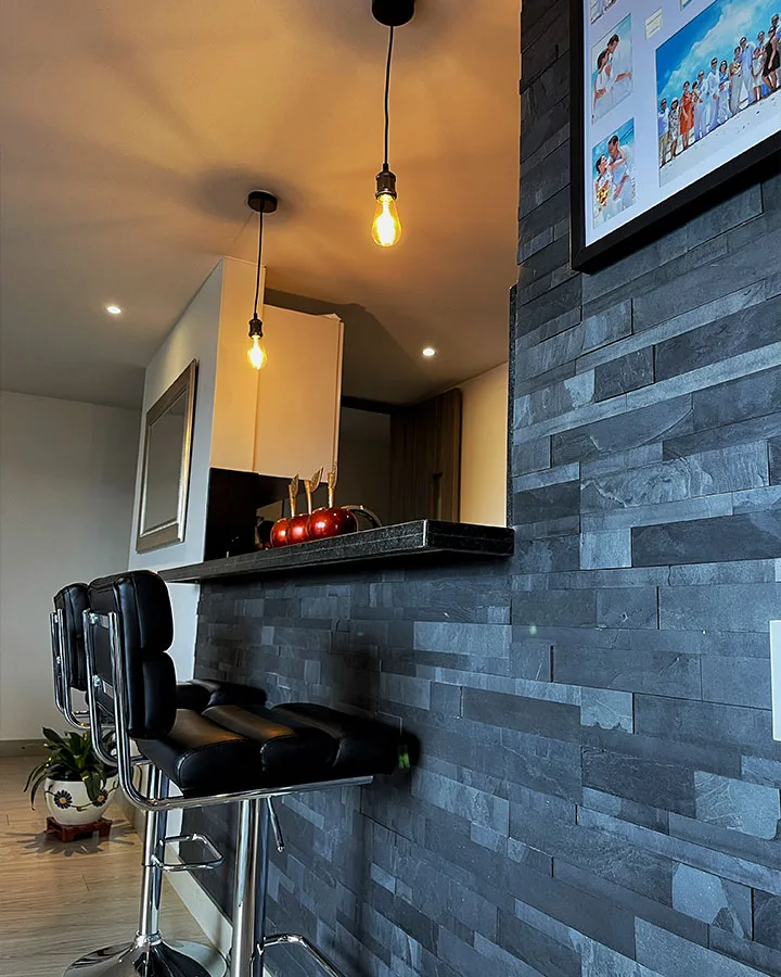 Cocina moderna con muro decorativo revestido en piedra flexible 3D negra autoadhesiva.