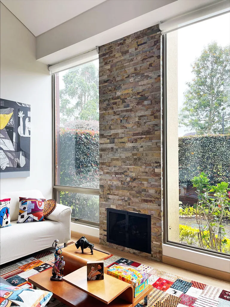 Chimenea decorada con piedra flexible 3D autoadhesiva StoneFlex Indian Rustic en sala con ventanales.