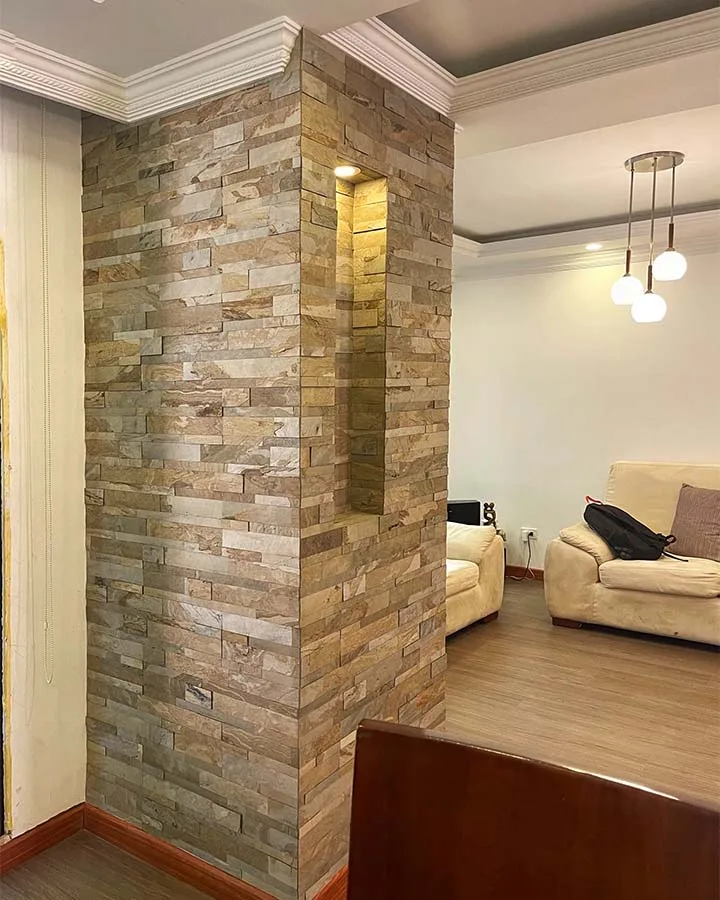 Chimenea decorada con piedra flexible 3D autoadhesiva StoneFlex Tan en sala residencial con ventanales.