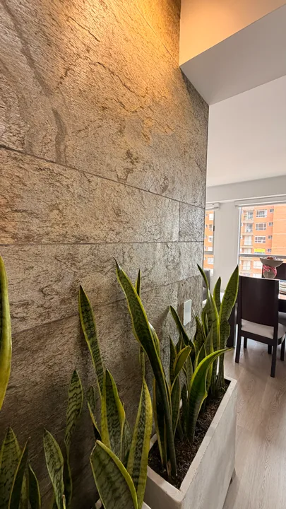 Detalle en perspectiva de pared interior revestida con paneles de piedra flexible Silver Shine Gold de StoneFlex, resaltando su textura y relieve bajo iluminación cálida.
