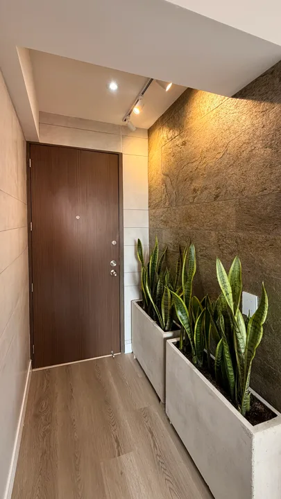 Revestimiento de paredes en pasillo de entrada combinando lámina de piedra flexible Silver Shine Gold en el lateral y paneles de concreto blanco de StoneFlex en el muro frontal.